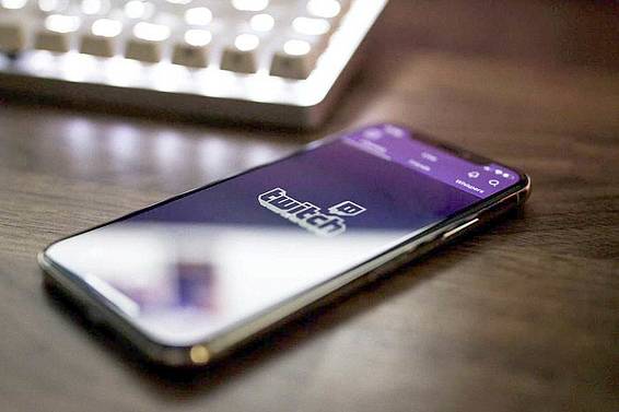 Geöffnete Twitch-App auf einem Smartphone vor einer Tastatur im Hintergrund